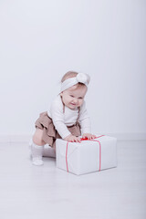 A beautiful, elegant girl received a gift. In a bright studio, a child plays and opens a gift..A picture of baby girl with big gift box