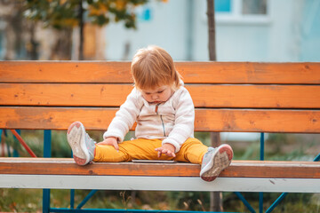 A cute little kid is sitting on a bench and watching cartoons. The concept of modern children's entertainment and education