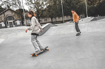 Girl riding skateboard in front and guy behind