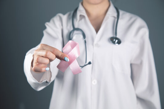 doctor holds a pink ribbon in his hand on a gray gray background