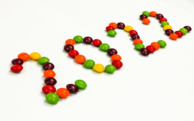 The inscription of the new year 2022 with multi-colored candy pins on a white background. Top view. 