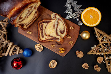 cozonac (sweet bread) with walnuts and Christmas decorations on black background