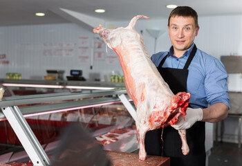 Skillful butcher processing carcase of young lamb for sale at butchery