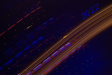 Abstract background of Christmas lights with long exposure. Colorful 2022 number on black background