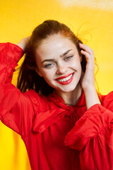 Naklejka premium smiling woman in red dress posing yellow background