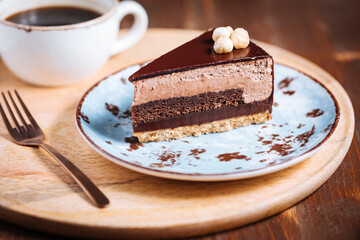 Chocolate hazelnut cake with five layers of biscuit and cream with chocolate glazing on top and whole nuts from Piemont. Served and decorated with coffee in background