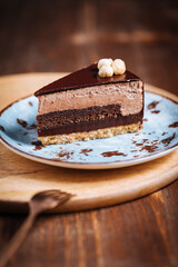 Chocolate hazelnut cake with five layers of biscuit and cream with chocolate glazing on top and whole nuts from Piemont. Served and decorated with coffee in background