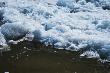 Texture of ice on a spring day under the sun. Puddle and glare from the sun. Amur river. Ice...