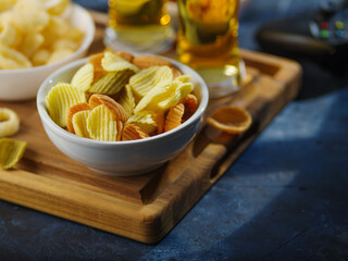 Potato chips, snacks, two glasses of light beer on a wooden tray. Brewery, pub, advertisement, restaurant, relaxing with friends, family, watching your favorite shows and sports programs.
