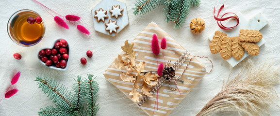 Wintertime holiday background. Gift box wrapped in craft brown paper. Natural dry oak and bunny...