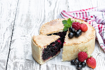 Freshly baked berry pie on white wooden table