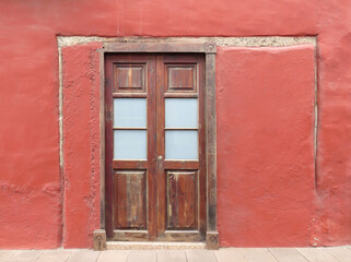 Fototapeta premium Traditional colonial house with red facade and wooden door. Historic town of Garachico. Tenerife Island. Canary Islands. Spain.