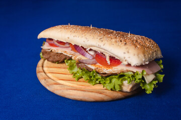 Meat sandwich with long bread on top of a blue table.