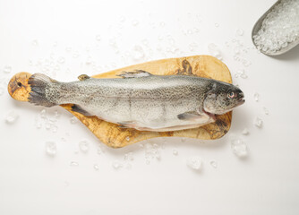 Fresh fish on a wooden cutting board on a white background. Pieces of ice. Minimalism. Fishing, supermarket, restaurant, hotel, culinary blog, advertisement, banner, poster.