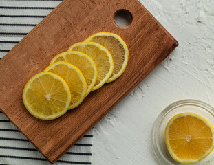 Freshly sliced lemon slices on a wood board on a striped napkin. Sliced lemon as an ingredient for...