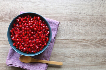 Bowl of fresh pomegranate seeds on wooden table. Top view.
