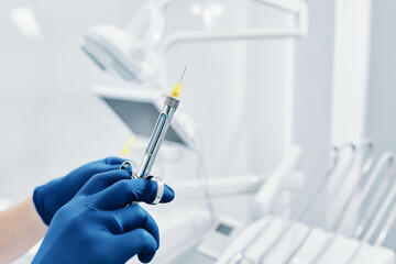 
a dentist holds a dental syringe in a dental clinic