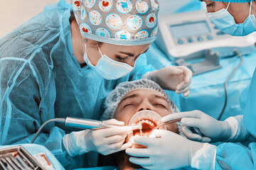 
2 women dentists perform dental implantation operations on a patient in a dental clinic in special...
