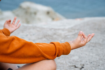 The pose of Buddha and jnana is wise. Yoga, mindfulness, wisdom. A close shot of the hands of a person doing yoga. Sports by the sea