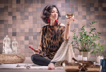 Image of an adult woman in yoga place. Playing on Tibetan singing bowls. The concept of yoga and...