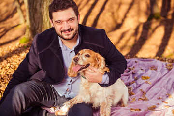 young man in coat portrait with dog in autumn forest with colorful leafs on background