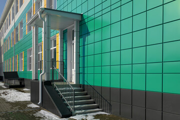 entrance group with flight of stairs and visor against the background of green aluminum ventilated...