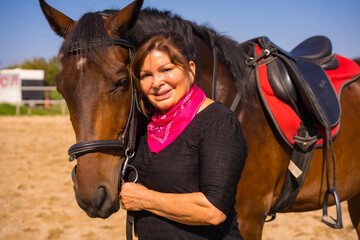 Obraz premium Portrait of an adult woman on a horse stroking a brown horse, dressed in South American outfits