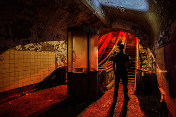 Urban explorer in dark and creepy old abandoned subway station