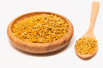 Bee pollen (pollen) in a wooden dish and a spoon.
