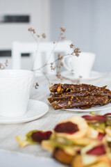 Fruit marshmallow and paste on a white table and white kitchen with dry oranges and dry flowers, cup ot tea on the table