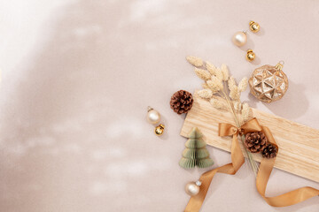 Stimmungsvolles, natürliches Weihnachtsarrangement im Lichtspiel mit Trockenblumen, Kugeln, Zapfen, Schleife und Weihnachtsdekoration auf Holz und Naturpapier, Querformat, Weihnachtskarte