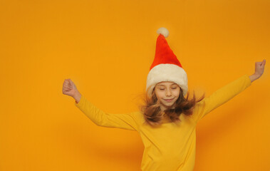Emotional cute little girl in santa hat on yellow background with a copy space.