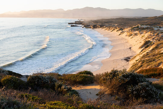 View from the cliffs over the sandy beach and waves breaking on shore.  