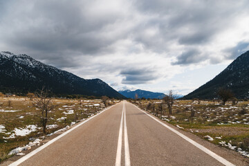 Empty asphalt road in the middle of mountainous area. Highlands of Greece, winter time. Freedom, travel concept.