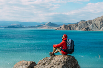 A man with a backpack on the background of the sea. Portrait of a man in tourist gear on the...