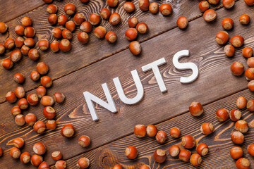 the word nuts laid with silver letters on wooden board background surrounded with scattered...