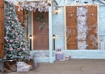 Winter view of a country house with Christmas decorations. Porch courtyard with Christmas porch, veranda, wreath, Christmas tree, garland. Merry Christmas and Happy New Year