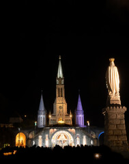 Fototapeta na wymiar Night shot of illuminated church of Lourdes in France, the place of apparitions of virgin Mary,