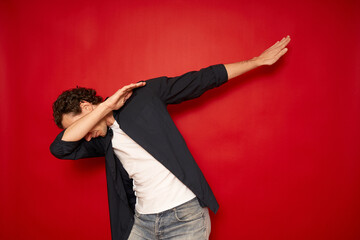 Happy man in casual making dab arms gesture on blank red studio background, funny white guy dabbing moving in internet meme pose celebrating victory having fun, dance school or triumph concept