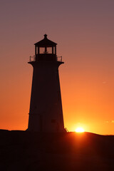 Silhouette shot of the Peggy's Cove Lighthouse during a beautiful sunset full of red and orange sky as the sun sets behind the horizon. 
Peggy's Cove Lighthouse, Halifax, Nova Scotia, Canada