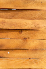 Light wooden boards without treatment on a street fence on a sunny day. Natural wood structure, vertical orientation