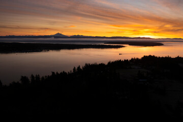 Dramatic Sunrise Over Lummi Island, Washington. With Mt. Baker on the Horizon. Intense colors and calm winds accompany this glorious autumnal sunrise across Hale Passage in the Salish Sea.