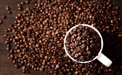 coffee beans in a white mug on a dark wooden background