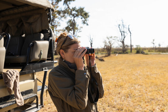 Woman using binoculars on a game drive in a nature reserve
