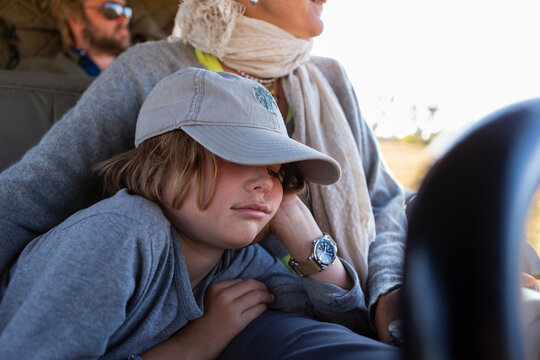 Eight year old boy in safari vehicle, sleeping beside his mother, in a safari jeep