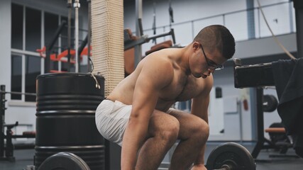 Fototapeta na wymiar An Arab man squats in the gym with a barbell.