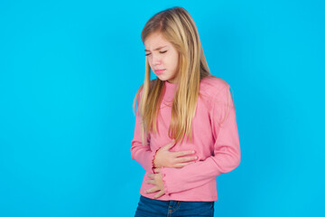 caucasian little kid girl wearing long sleeve shirt over blue background got stomachache