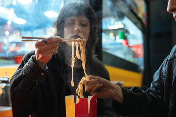 Girl looking at the noodles while holding it at the sticks and preparing to eating