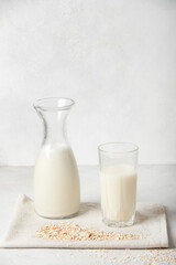 Alternative vegetable oat milk is poured into a bottle and glass cup, next to oatmeal on a white background. Healthy beverages healthy concept