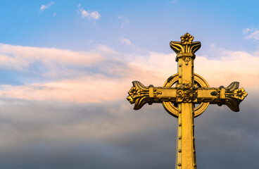 Fototapeta na wymiar The historic gilded cross in front of the Basilica of the Apparitions of Mary in Lourdes, France